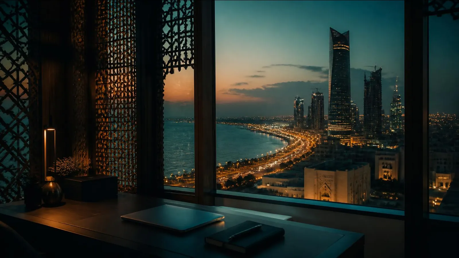 A coastal skyline at dusk, seen from an office framed by traditional mashrabiya woodwork.